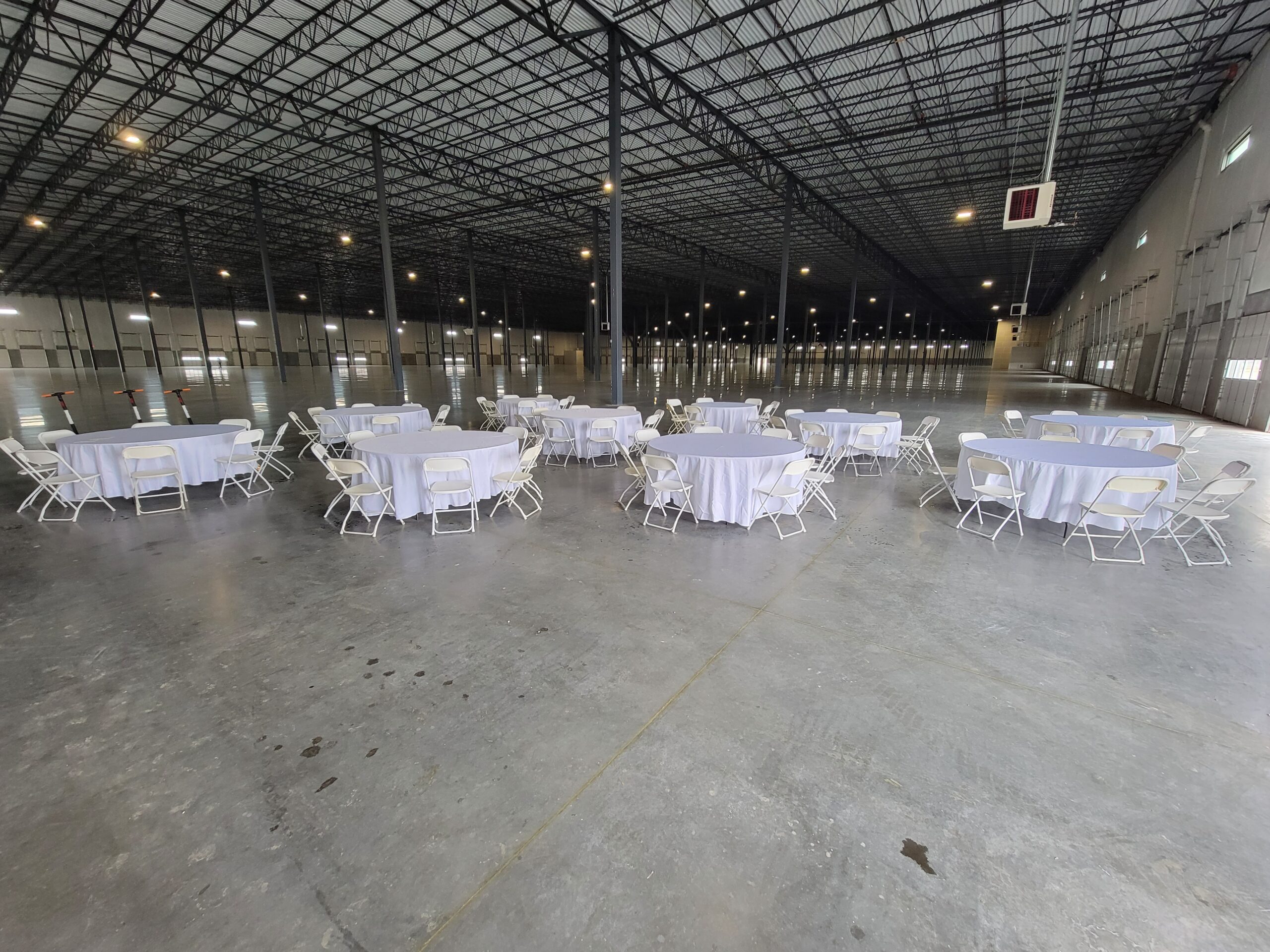 Round tables and white chairs arranged by Bounce N Around for a large Colorado event venue