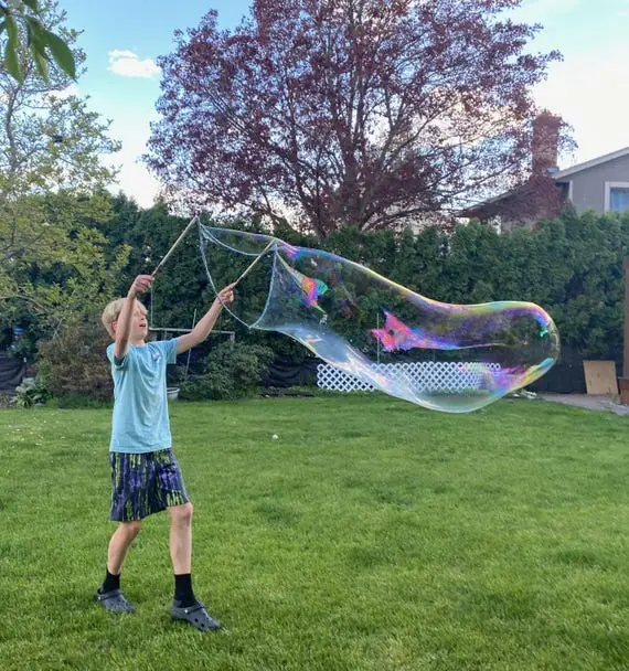 A young guest creating a giant bubble outdoors at a Colorado celebration